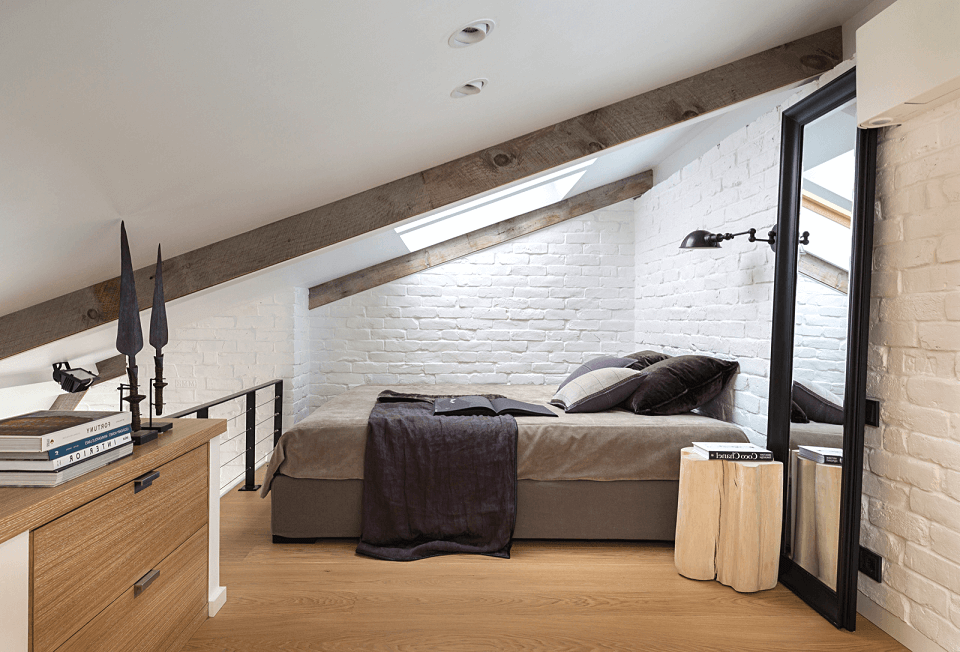 Bright mansard bedroom with bedside lamp