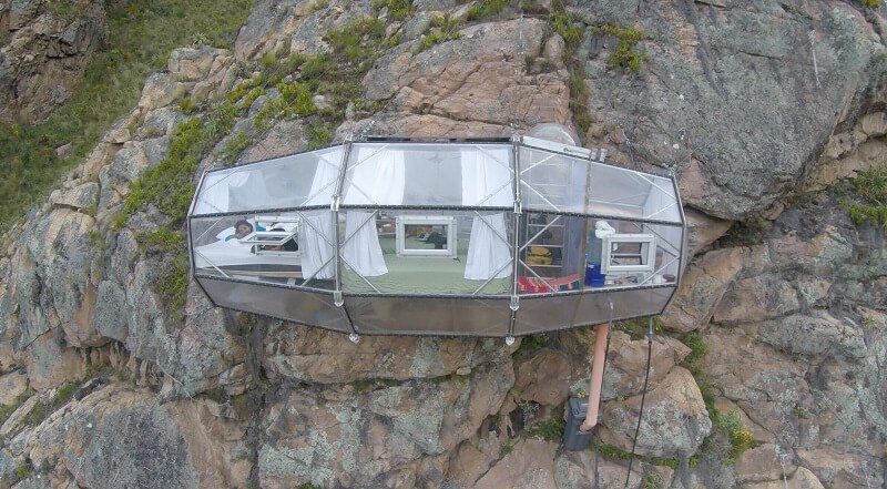 transparent hotel capsule on a sheer cliff