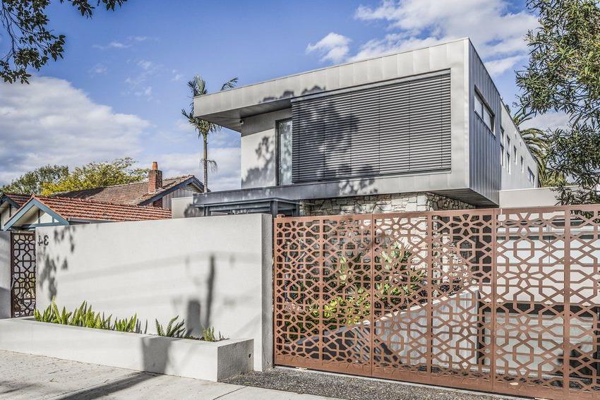 Openwork gates and a wicket made of metal are harmoniously combined with the design of the building and the adjacent territory